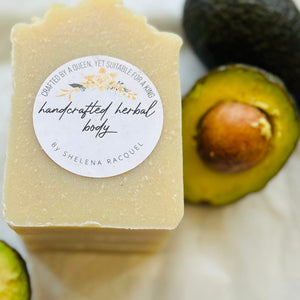 Handcrafted herbal body soap with an avocado on a white surface
