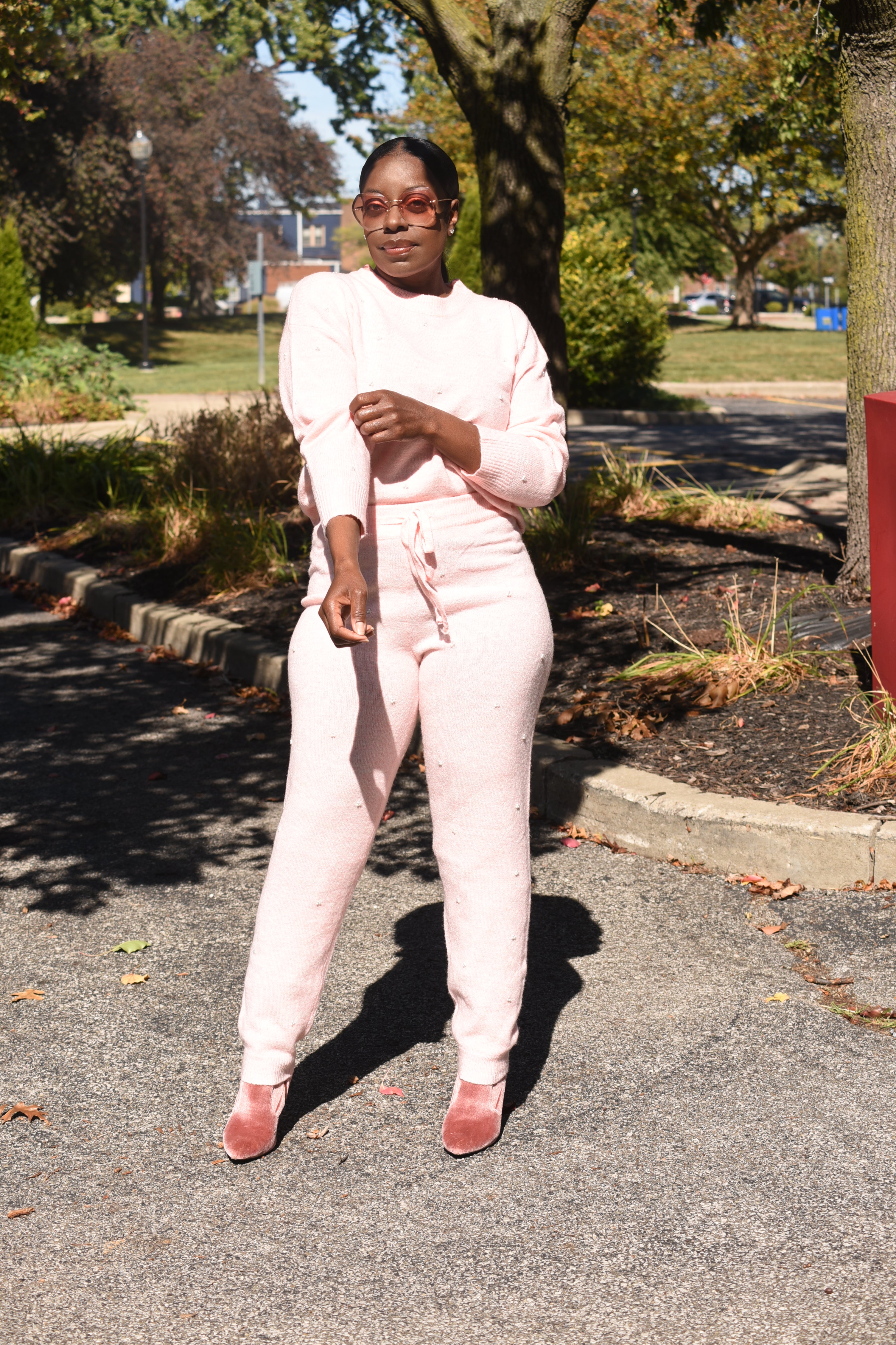 Person in a pink pearl outfit standing on a road with trees and grass in the background